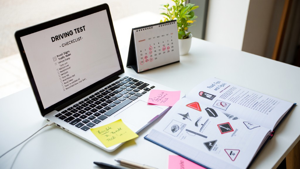 Schreibtisch mit Laptop Checkliste Führerschein, Buch Verkehrszeichen und Kalender — Planung